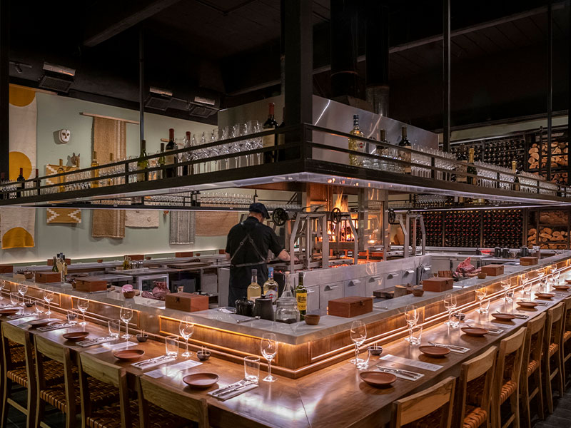 Chef preparing the dishes on the custom-made parrilla in front of the guests in Fogon Asado