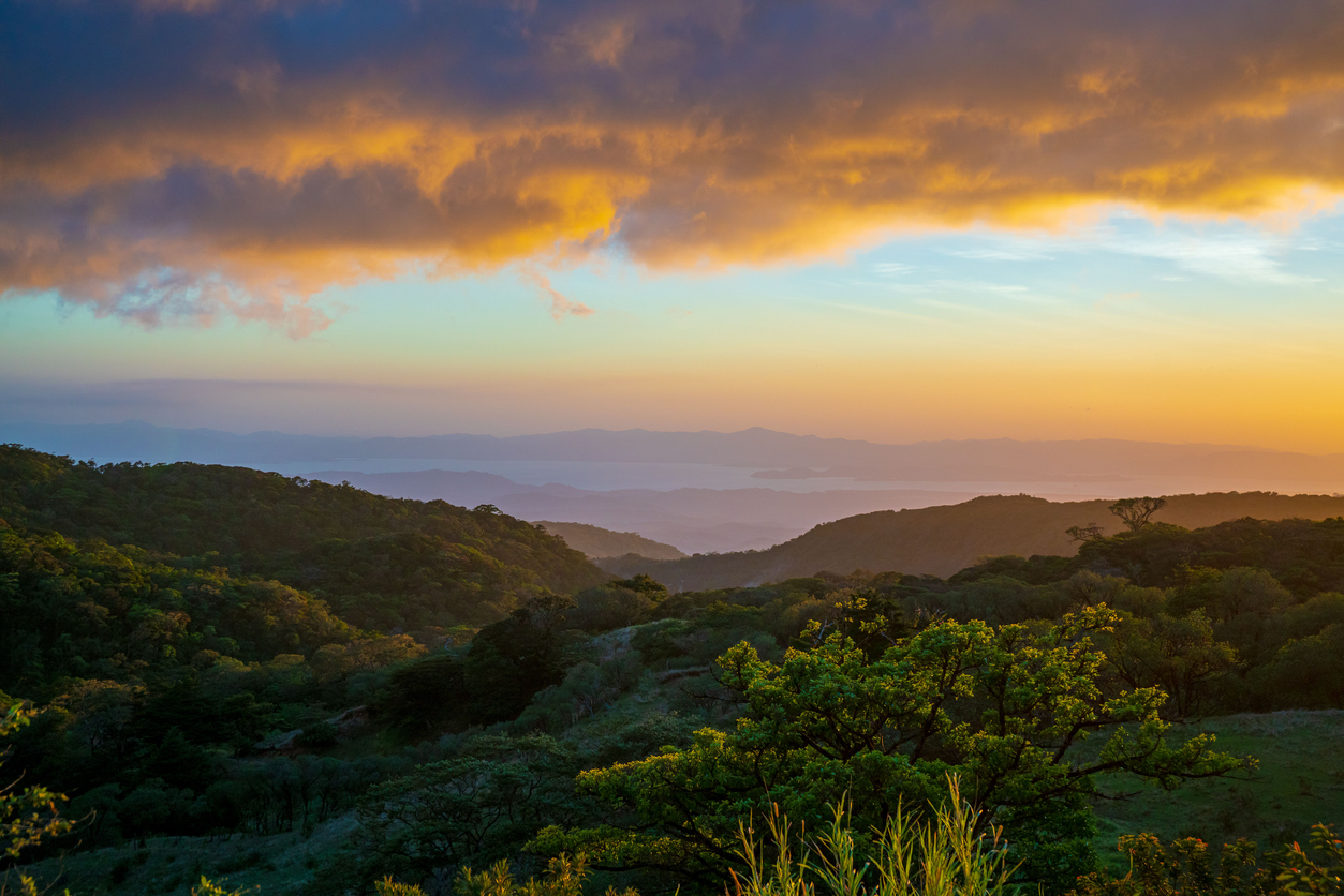 Aerial view of a golden bright sunset sky over rural fields and mountains in Monteverde